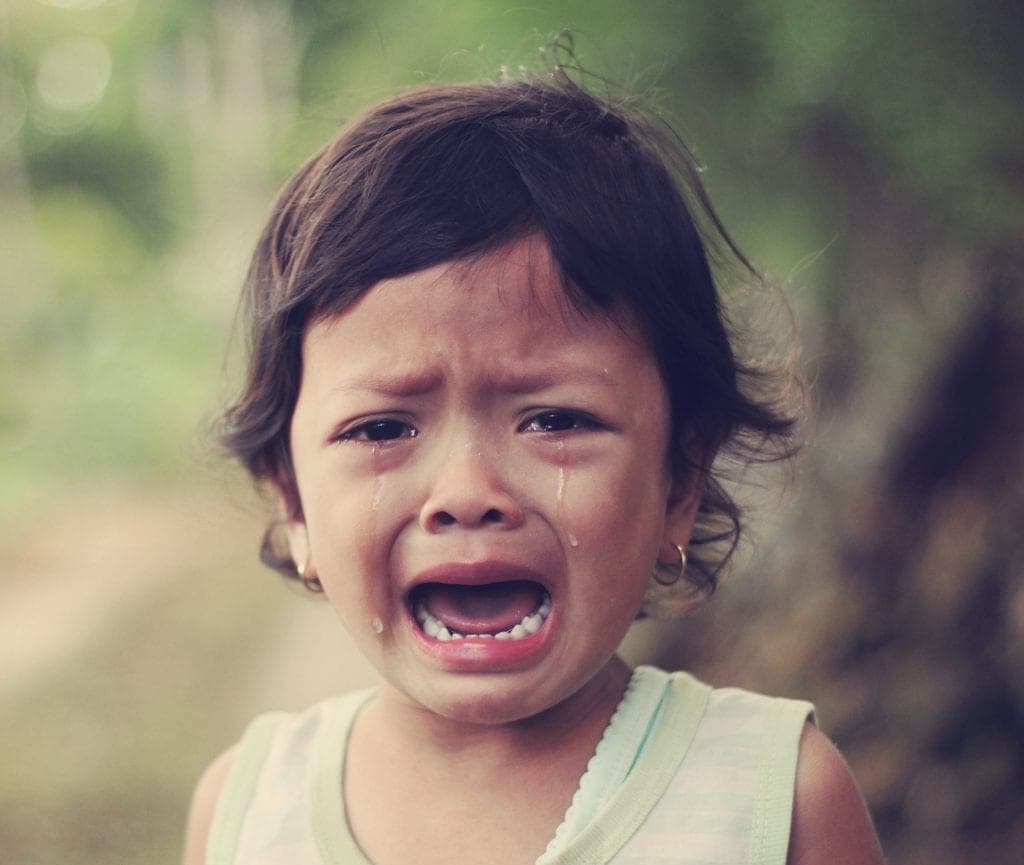 Closeup of a dark-haired child crying because she is afraid of the dentist