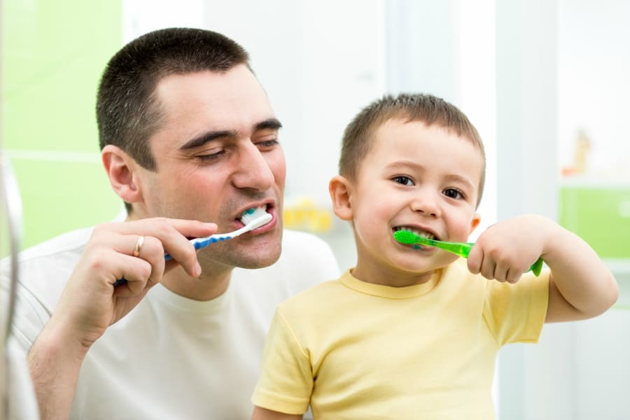 Father and son smiling and brushing their teeth