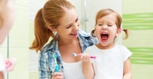 Mother and daughter smiling as they brush their teeth