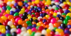 Close-up of a layer of black, purple, white, yellow, red, pink, green, and orange jelly beans that can cause cavities