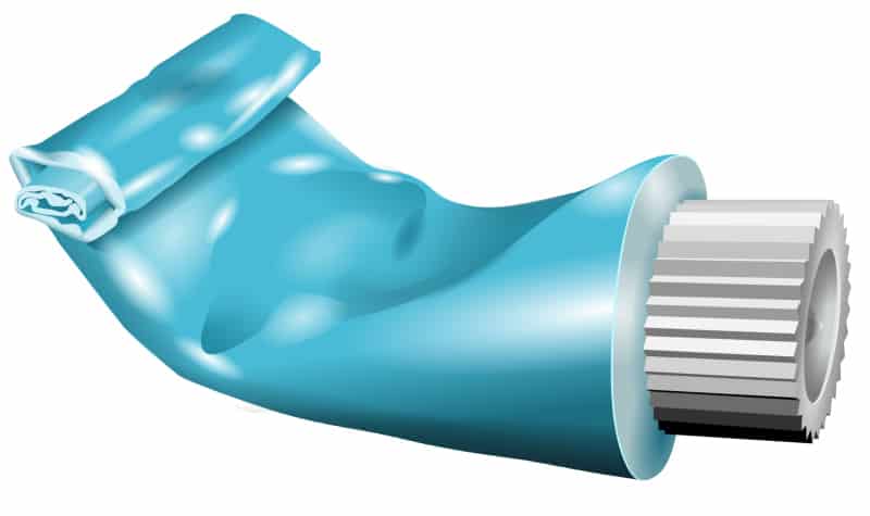 Partially squeezed blue tube of toothpaste with a white corrugated cap against a white background